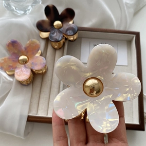 Three acetate flower hair claws in iridescent white, tortoiseshell brown and pink purple