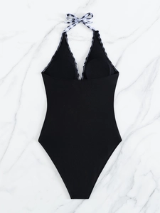 Flat lay of black one-piece swimsuit with monochrome checkered halter neck details