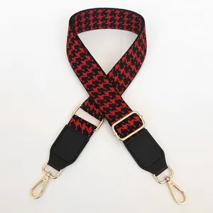 Detail of red and black houndstooth strap with golden swivel hook and leather ends