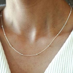 Close-up of minimalist silver bead chain necklace worn on a neck for styling