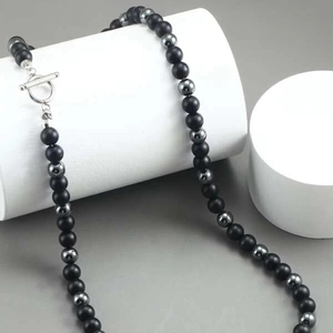 Detail of beaded necklace with matte black stones and silver OT toggle clasp on display