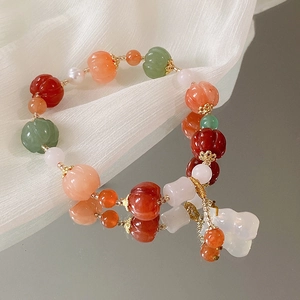 Detail eines Vintage-Perlenarmbands mit bunten geschnitzten Perlen und weißem Kürbisanhänger