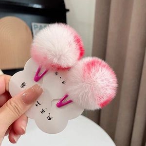 Close-up of cute pink and white gradient faux fur pom pom hair clips on a card