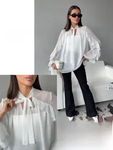 Detail view of semi-transparent white chiffon shirt with elegant bow tie and ruffled cuffs