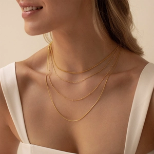 Close-up of layered gold-plated stainless steel necklaces with beaded detail on model
