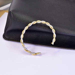 Detail of twisted cable cuff bracelet in two-tone gold and silver stainless steel
