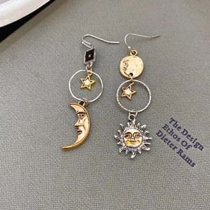 Dettaglio di orecchini asimmetrici sole e luna con finiture in oro e argento metallico
