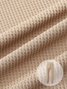 Detail of beige waffle knit fabric texture and elastic drawstring waistband on trousers