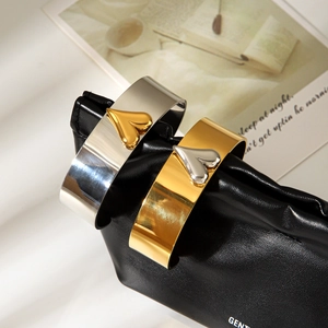 Two-tone stainless steel open bangle with contrasting heart design on black leather background