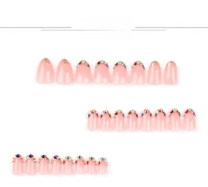 Detailed view of pink press-on nails with sparkling rhinestones and gold glitter accents