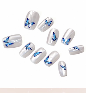 Detailed view of 10-piece pearl white press-on nails with blue butterfly and cat eye design