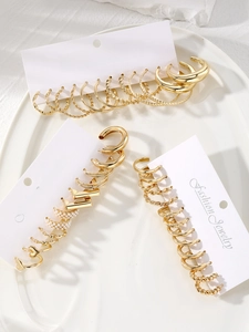Macro view of a 16-piece gold earring set with pearls on a white ceramic tray