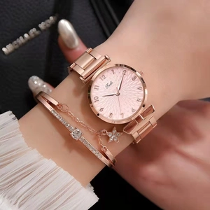 Close-up of rose gold watch with pink sunray dial paired with a star charm bracelet