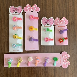 Flat lay of colorful children's hair clip sets on pink display cards on wooden surface