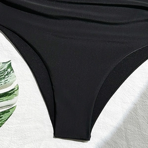 Close-up of black bikini bottoms featuring high-waisted ruched texture and elastic fabric