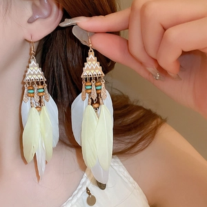 Detail of bohemian tassel earrings with feathers and beads on model's profile
