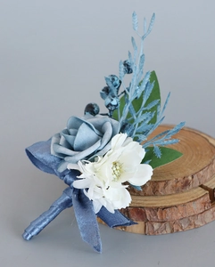 Detailed view of blue rose boutonniere with berries on a rustic wood slice base