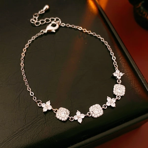 Detail of silver floral and square crystal links on black leather surface
