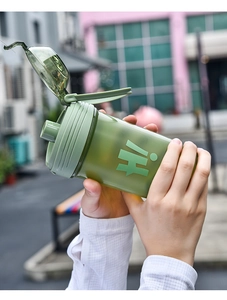 Close-up of portable green plastic fitness cup with straw and Hi logo in hand