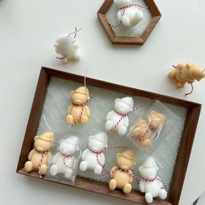 Detail of miniature Christmas bear candles with festive hats and decorative cords
