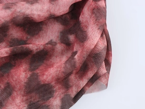 Detailed close-up of red and black tie-dye mesh fabric with sheer breathable texture
