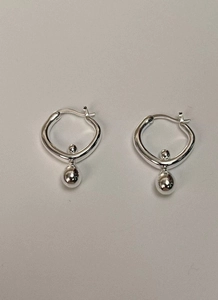 Detail view of silver spherical drop earrings with a polished metallic finish and modern style