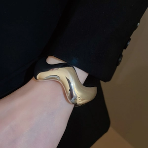 Dettaglio del bracciale dorato a onde con finitura a specchio lucida su sfondo nero
