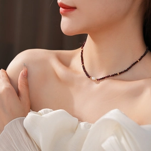 Detail of red garnet choker necklace featuring a white freshwater pearl and gold accents