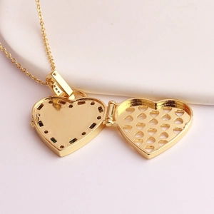Macro shot of an open golden heart locket necklace with intricate hollow grid detail