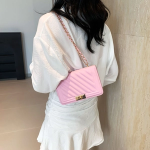 Pink V-quilted shoulder bag with gold chain strap worn over a white dress