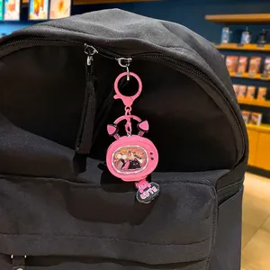 Pink cat-themed vintage TV keychain with glowing feature hanging on a black backpack