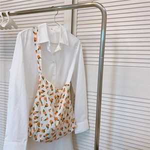 Détail d'un sac en coton à fleurs avec motifs tulipes suspendu sur une chemise blanche