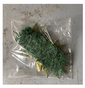 Detail view of a green faux pine wreath with gold accents in clear plastic packaging