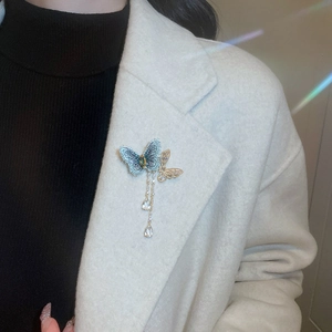 Detail of embroidered blue butterfly brooch with rhinestone tassels on a white coat