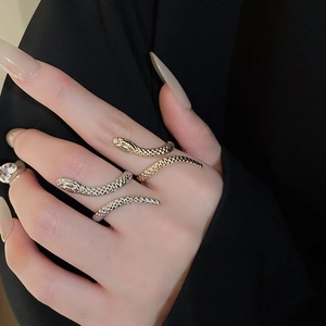Close-up of gold and silver snake rings with detailed scale texture on model hand