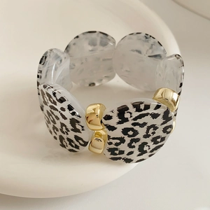 Macro detail of leopard print acrylic beads and golden metal spacers on a stylish bracelet