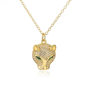 Macro shot of gold-plated leopard head pendant with sparkling zircon and green eyes