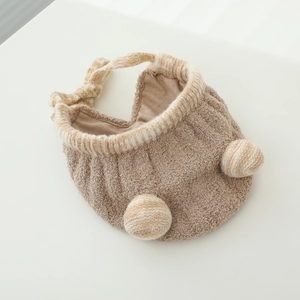 Detailed view of plush baby winter hat with double pom-poms and soft chin straps