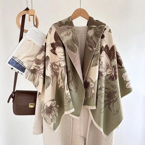 Detail of soft cashmere-like scarf showing green magnolia floral patterns and short fringes