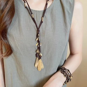 Detailed close-up of a model wearing the gold leaf pendant necklace and bracelet set