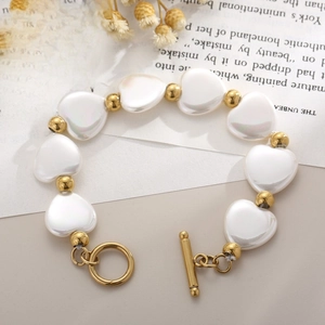 Bracelet coeur en nacre dorée avec fermoir à bascule OT sur fond papier vintage