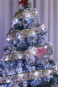 Detail of LED Christmas ribbon lights with gold stars wrapped on a snowy tree