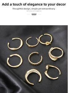 Detailed set of 8 gold minimalist rings and ear cuffs displayed on black silk fabric