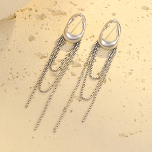 Macro shot of silver geometric tassel earrings with zircon on beige stone surface