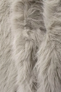 Detailed close-up of light grey faux fur texture and a hidden hook fastener on a vest