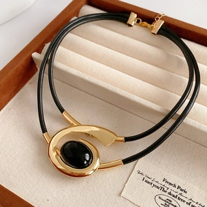 Detail of a gold abstract spiral necklace with an oval black stone in a jewelry box