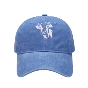 Detail of white cow head embroidery on washed blue cotton fabric of a baseball cap