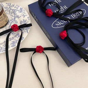 Detail of elegant red ribbon rose hair accessory and choker set in vintage scene