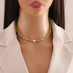 Beaded necklace with green and gold beads and a white pearl shown on a model neck