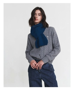 Detail shot of heavy blue knitted wool scarf paired with a grey cable knit cardigan
